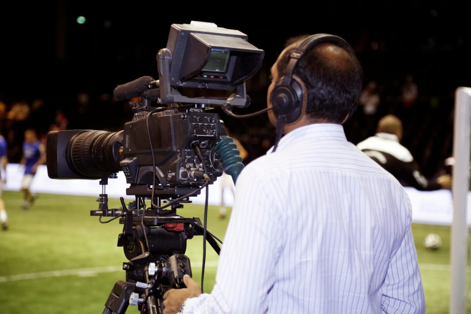 A cameraman filming a soccer match in a stadium, capturing the action on video.